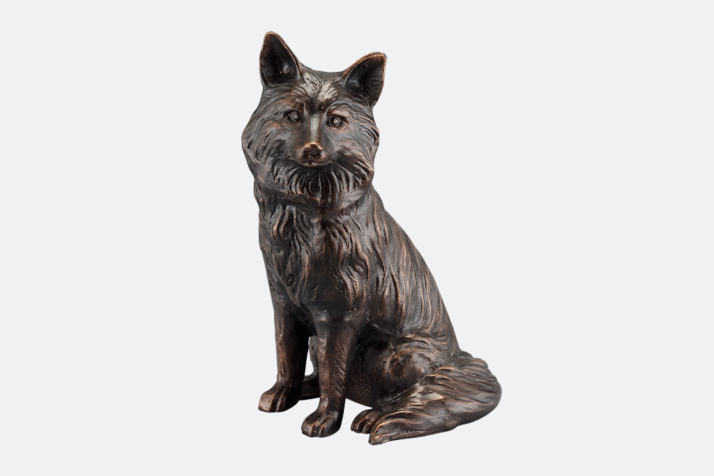 The front of a brown sculpture of a fox sitting.