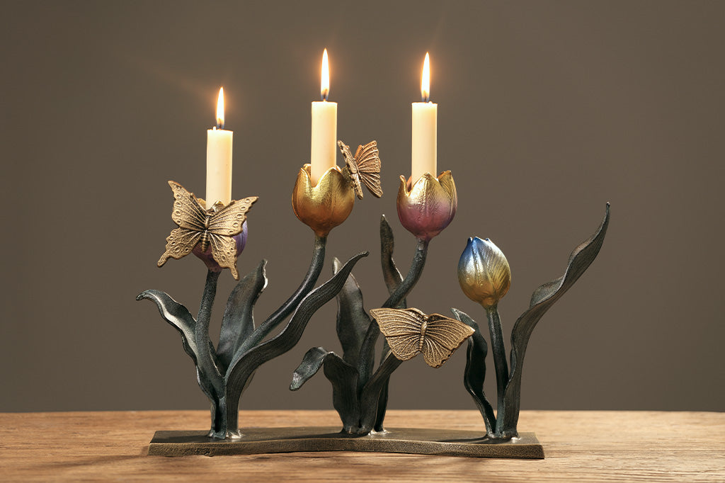 A candleholder sculpture of 4 gold, red, pink, and blue colored tulips with golden butterflies.