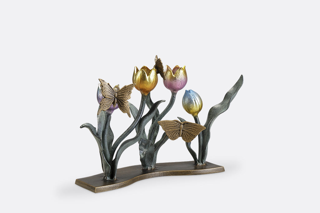 A candleholder sculpture of 4 gold, red, pink, and blue colored tulips with golden butterflies.