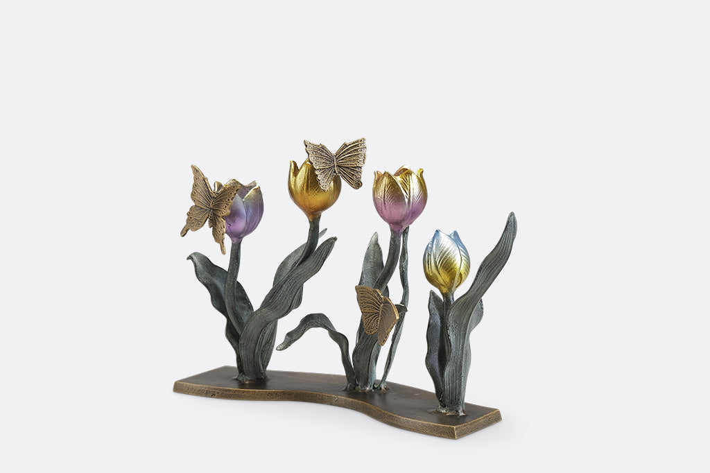 A candleholder sculpture of 4 gold, red, pink, and blue colored tulips with golden butterflies.