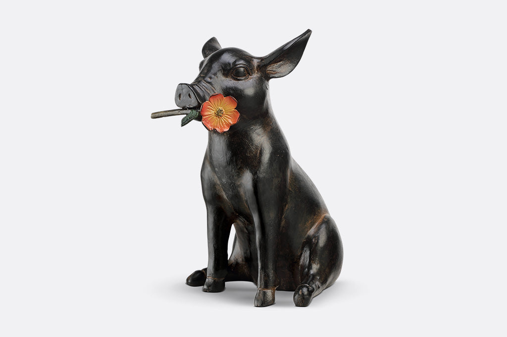 Pig sculpture with a flower in its mouth on a white background