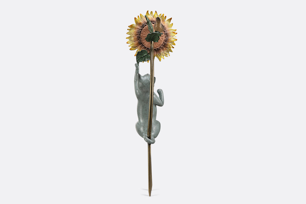 Garden stake of a cat reaching for a flower with a bird peering at it.