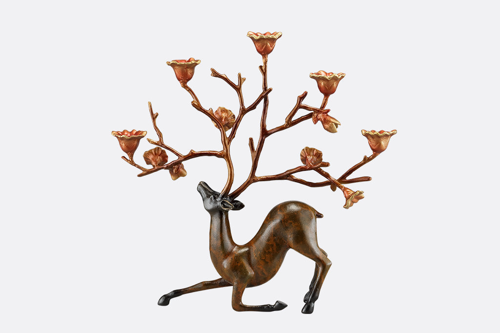 A sculpture of a kneeling stag with flowers on it's antlers which act as candle holders.