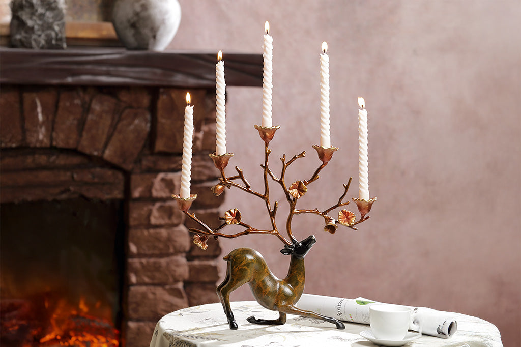 A sculpture of a kneeling stag with flowers on it's antlers which act as candle holders.
