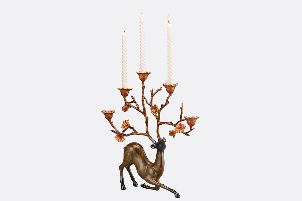 A sculpture of a kneeling stag with flowers on it's antlers which act as candle holders.