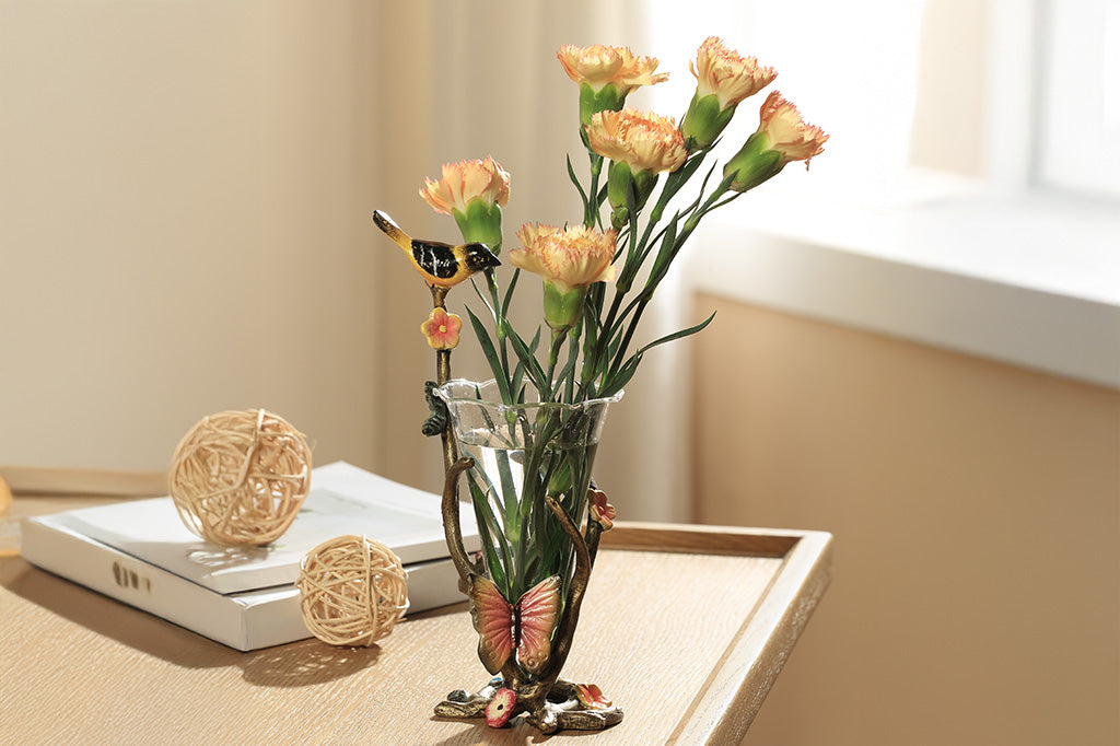 A sculpture vase of a bird and butterfly sat on a branch.