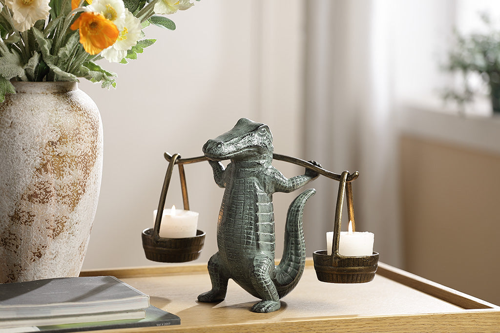 A sculpture of an alligator holding up two buckets.