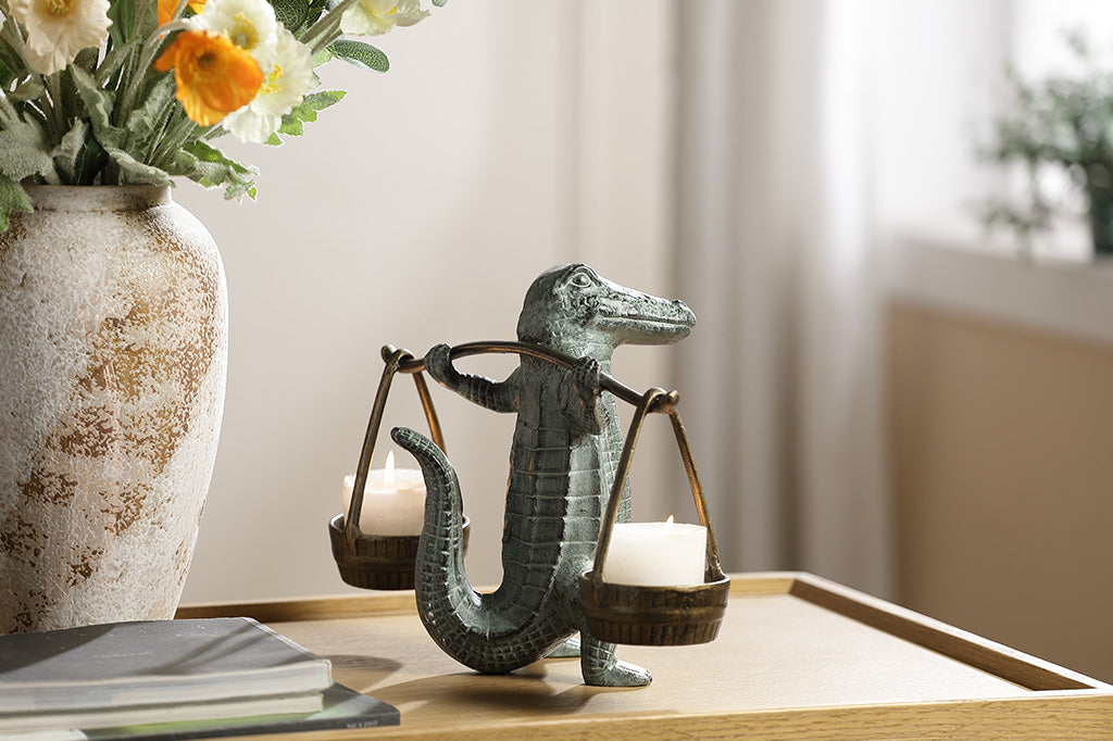 A sculpture of an alligator holding up two buckets.