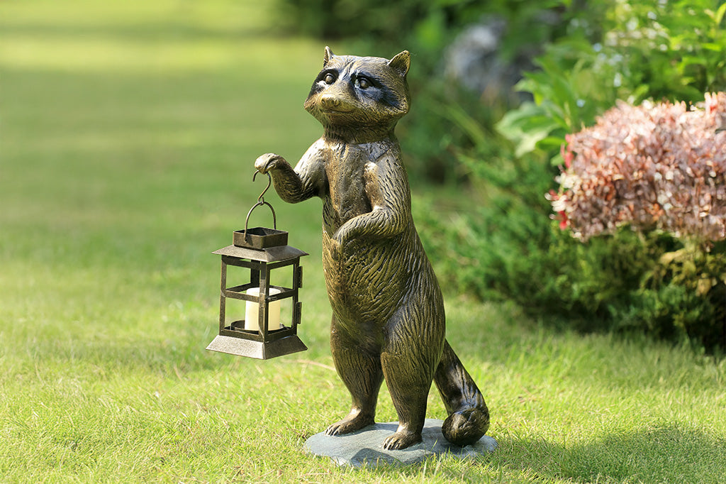 Statue of a raccoon holding a lantern on grass