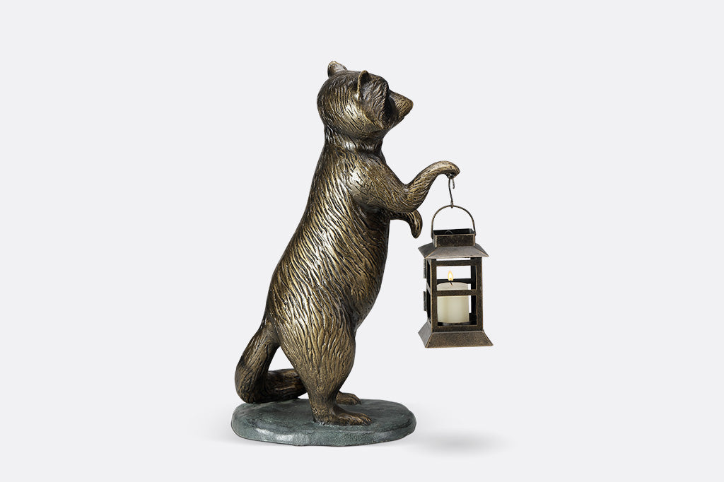 Sculpture of a raccoon holding a lantern on a white background
