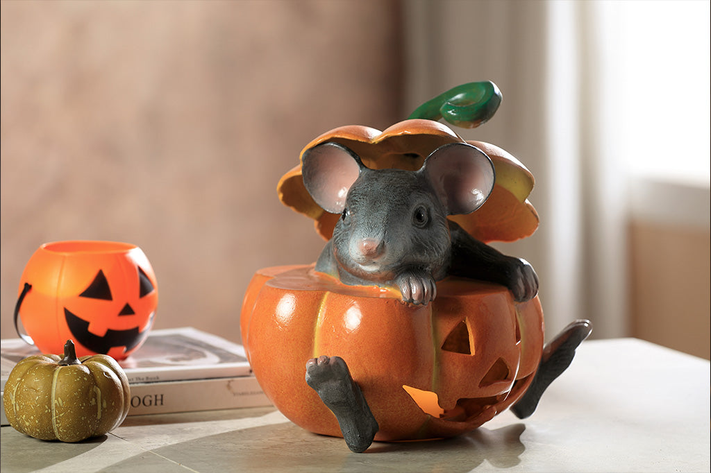 cast metal gray mouse in jack o lantern set on counter with lit votive candle inside holder, shown on counter with halloween decor