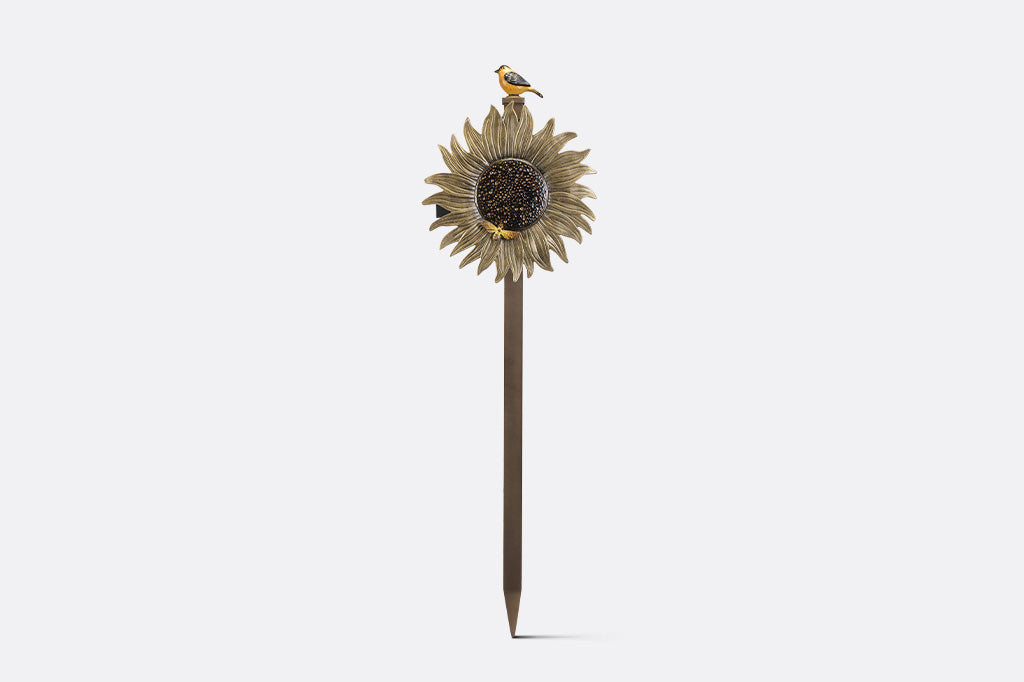 A garden stake hose holder with a sculpture of a sunflower and bird.