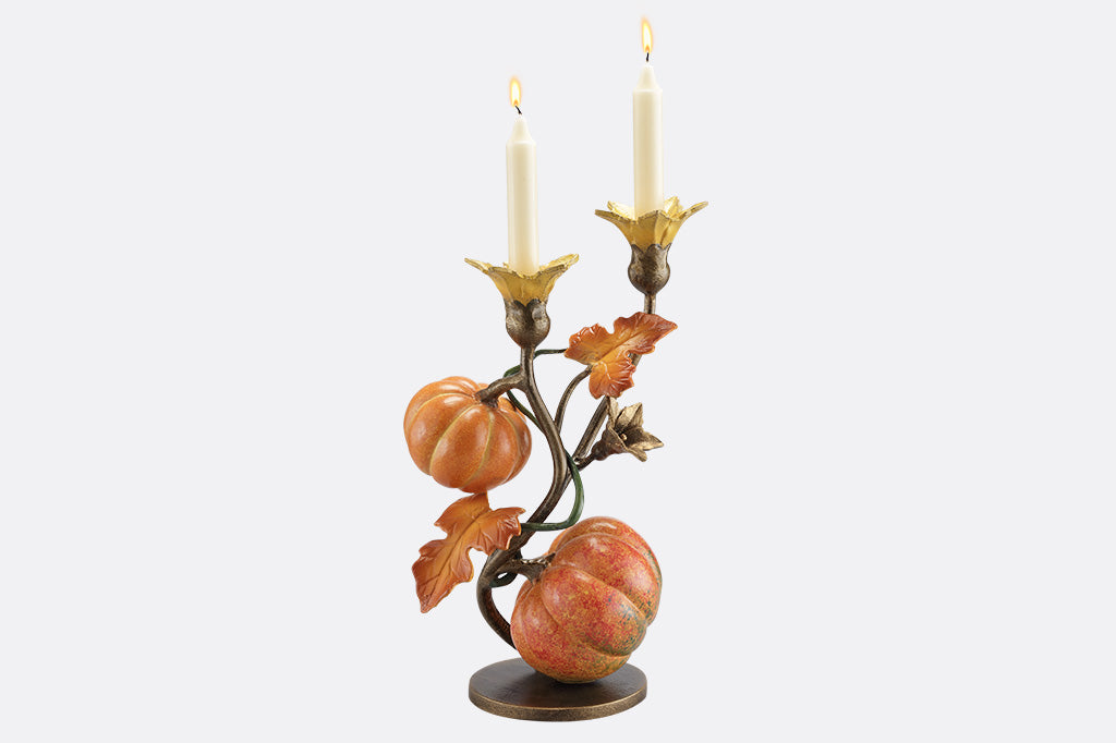 A candleholder statue of a vine blooming two pumpkins.