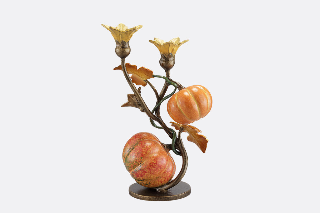 A candleholder statue of a vine blooming two pumpkins.