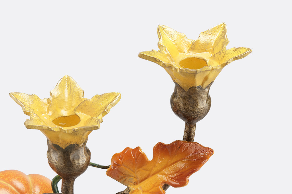 A close up of the two flowers on a candleholder statue of a vine blooming two pumpkins.