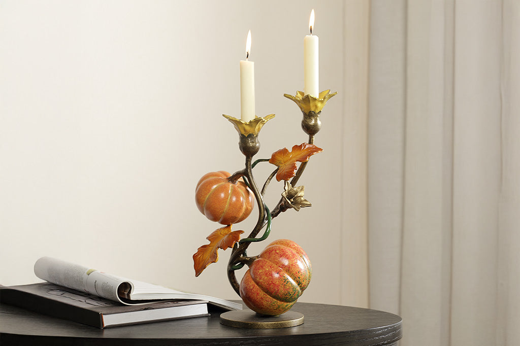 A candleholder statue of a vine blooming two pumpkins placed on a table.