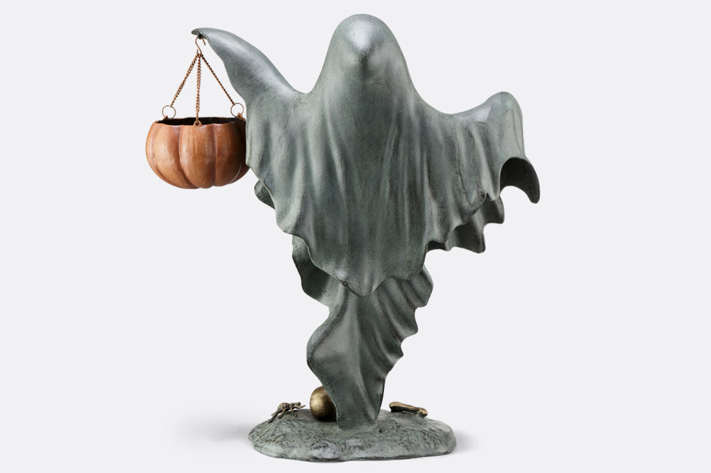 cast metal smiling ghost holding jack o lantern face back 
