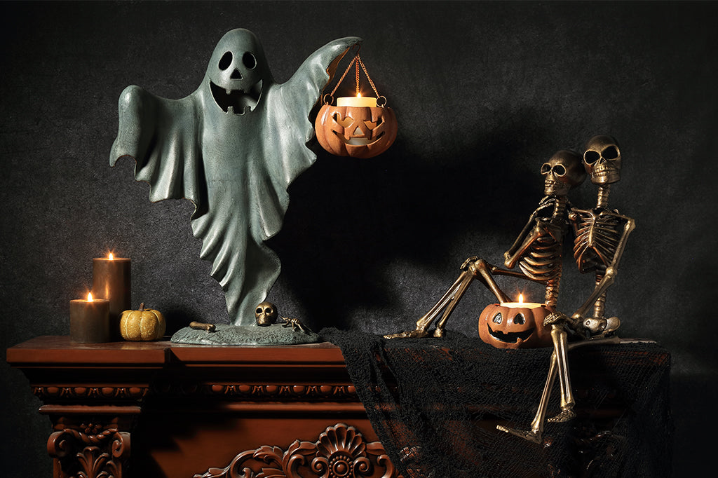 cast metal smiling ghost holding jack o lantern with candle inside sitting alongside with eternal love with boo bucket 