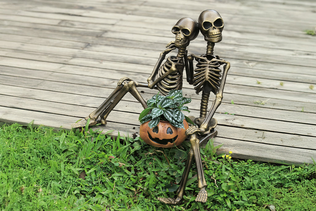 cast metal skeleton couple with jack o lantern with plant inside lantern 
