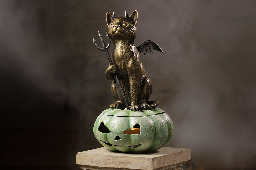 cast metal devil cat sat on green pumpkin 