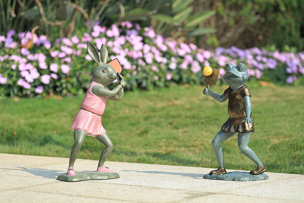 Sculpture of a frog holding a paddle  and a sculpture of of a bunny playing pickleball.