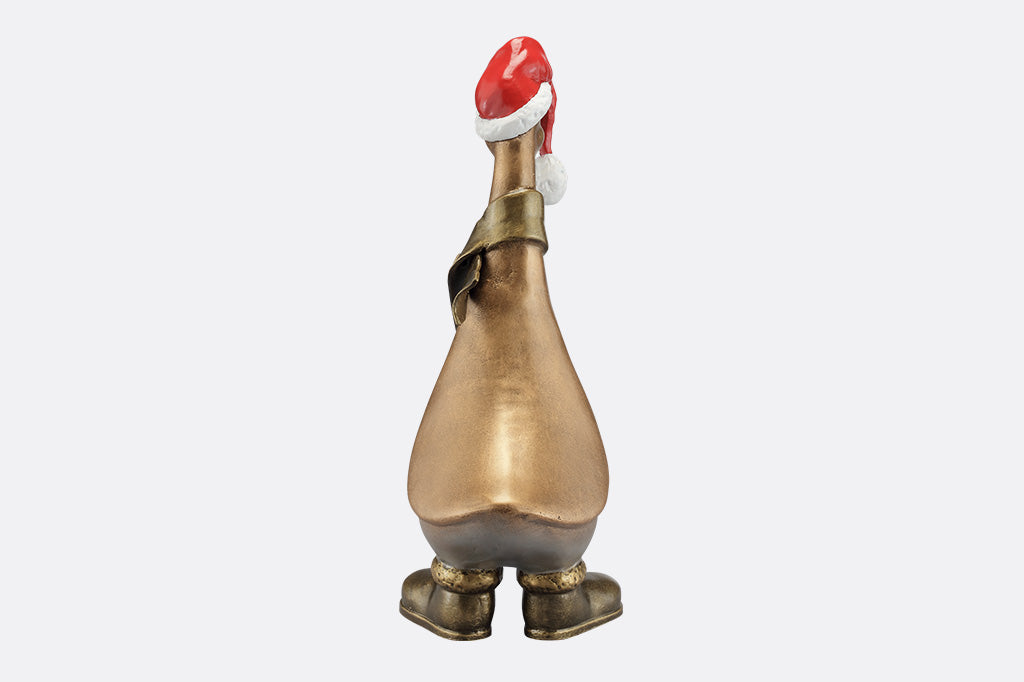 The back of a statue of a duck wearing a scarf, boots, and oversized santa hat covering his eyes.