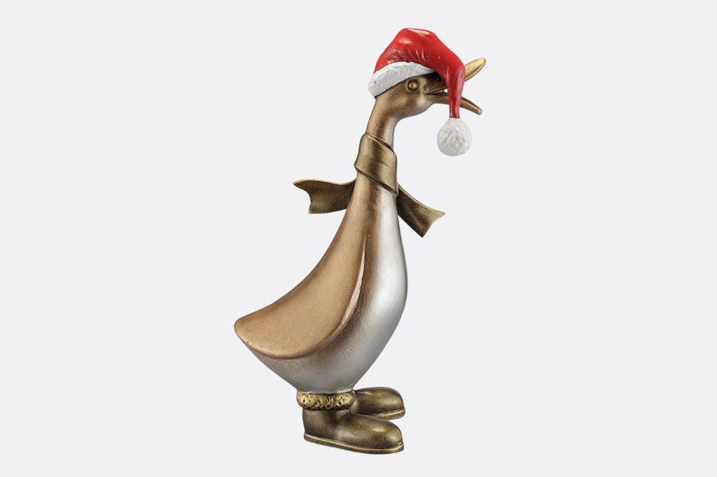 The side of a statue of a duck wearing a scarf, boots, and oversized santa hat covering his eyes.
