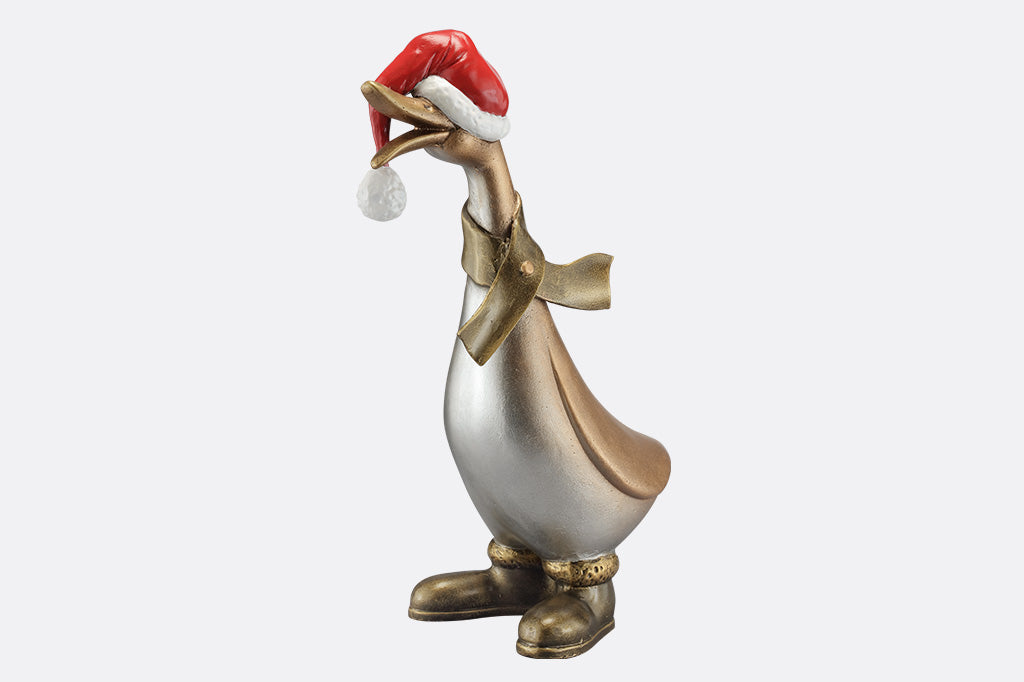 The side of a statue of a duck wearing a scarf, boots, and oversized santa hat covering his eyes.