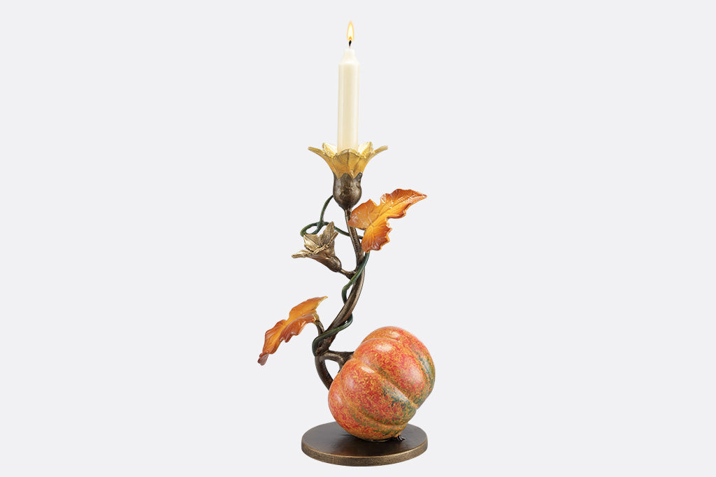 A candleholder statue of a blooming vine with a single pumpkin.