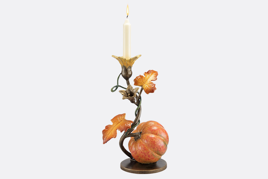 A candleholder statue of a blooming vine with a single pumpkin.