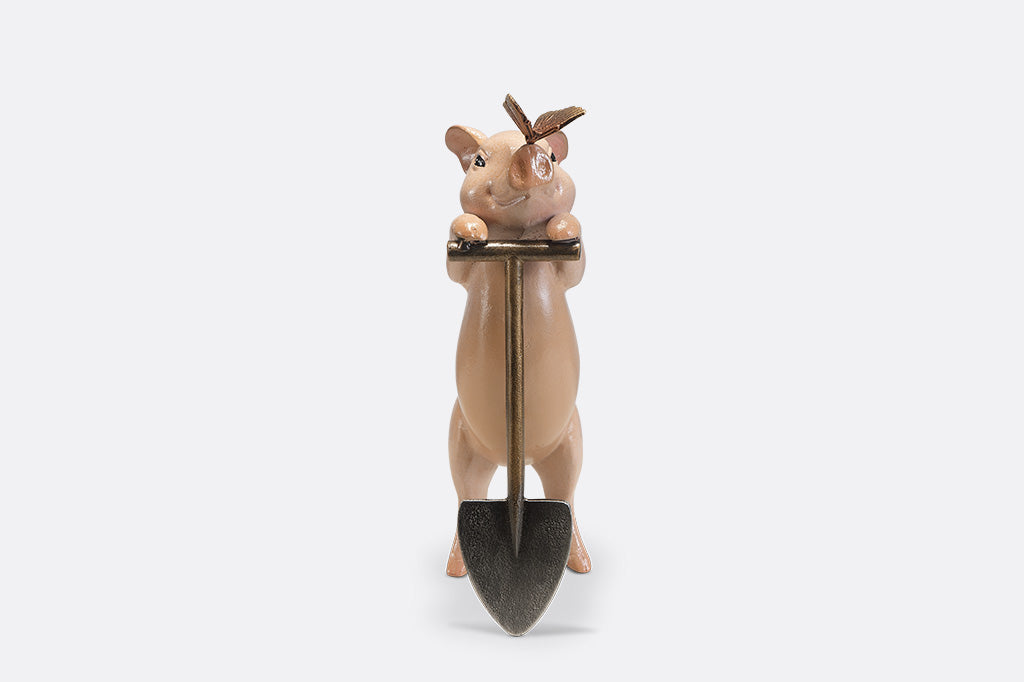 A sculpture of a pig holding a shovel with a butterfly landing on it's nose.