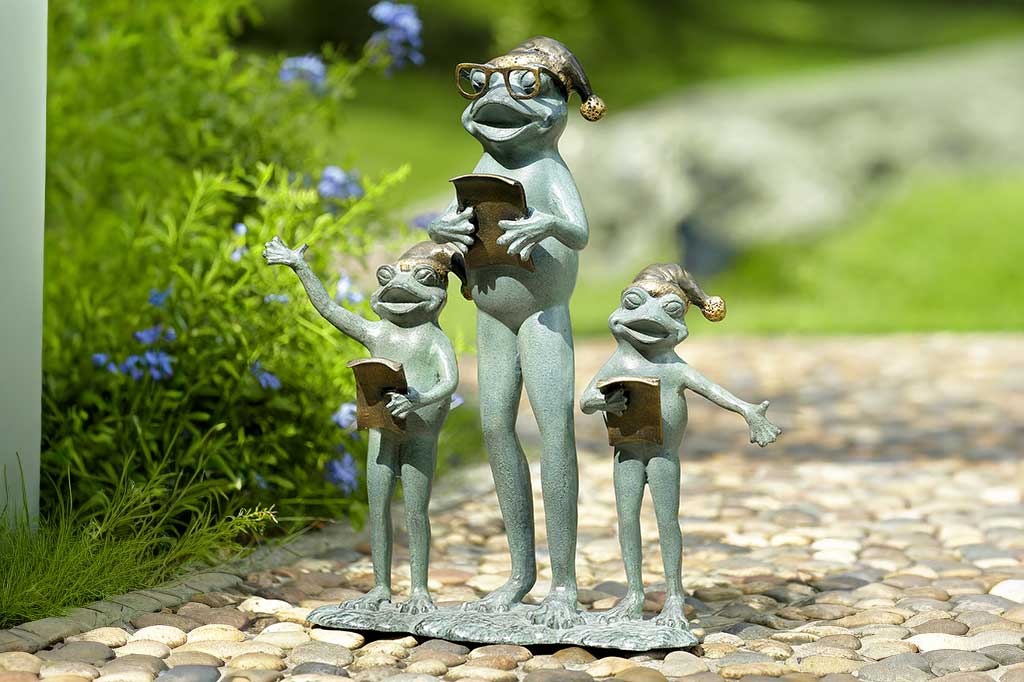 garden statue of 3 frogs with santa hats; they hold music as they carol in a garden
