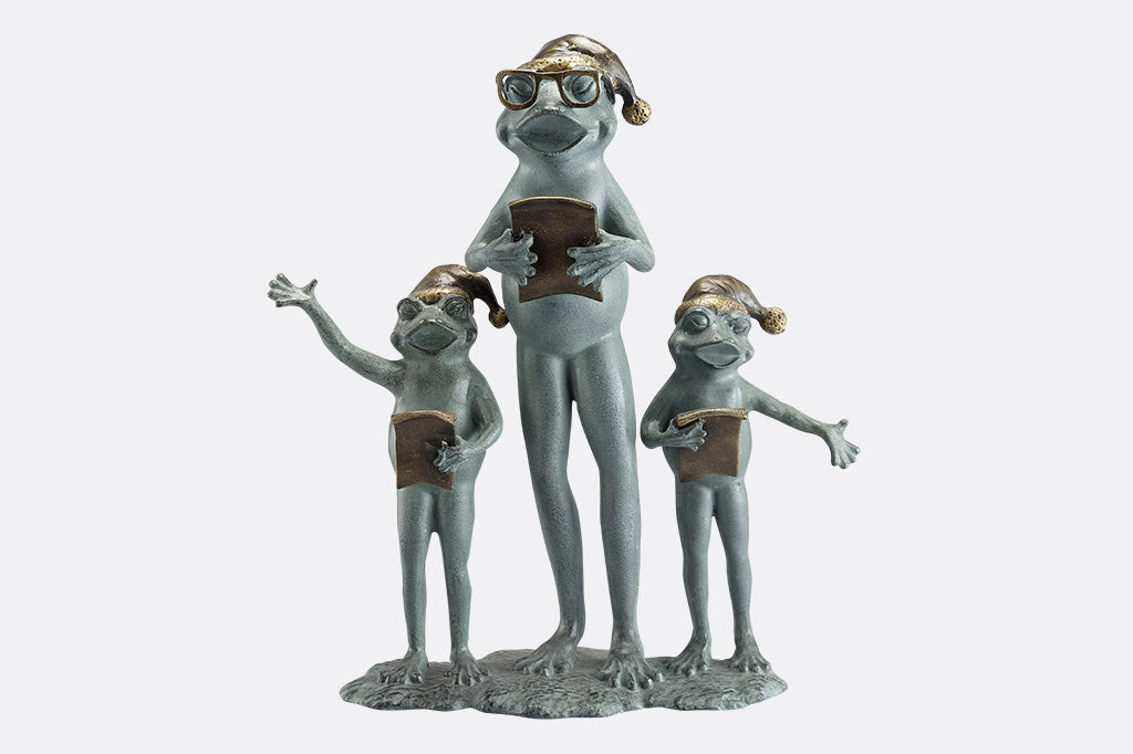 Sculpture of a frog family with santa hats singing carols on a white background