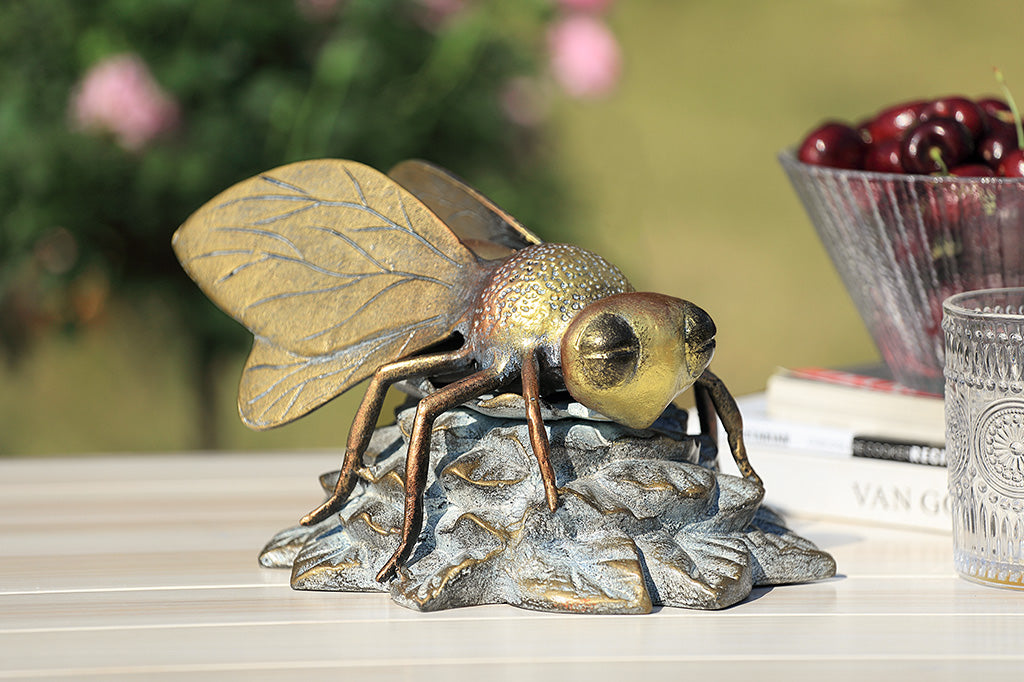 A statue of a bee landing on a flower.