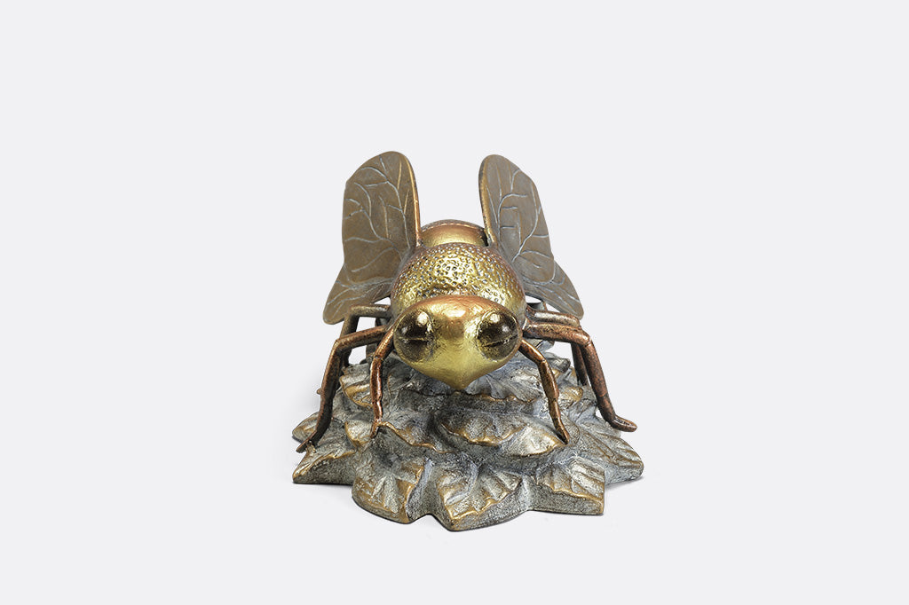 A statue of a bee landing on a flower.