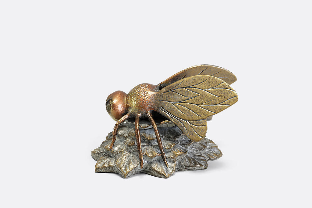 A statue of a bee landing on a flower.