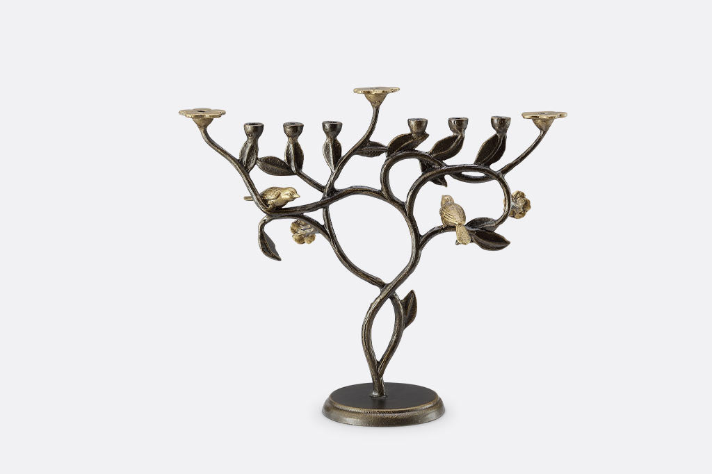 Menorah of cast metal with bird designs on a white background