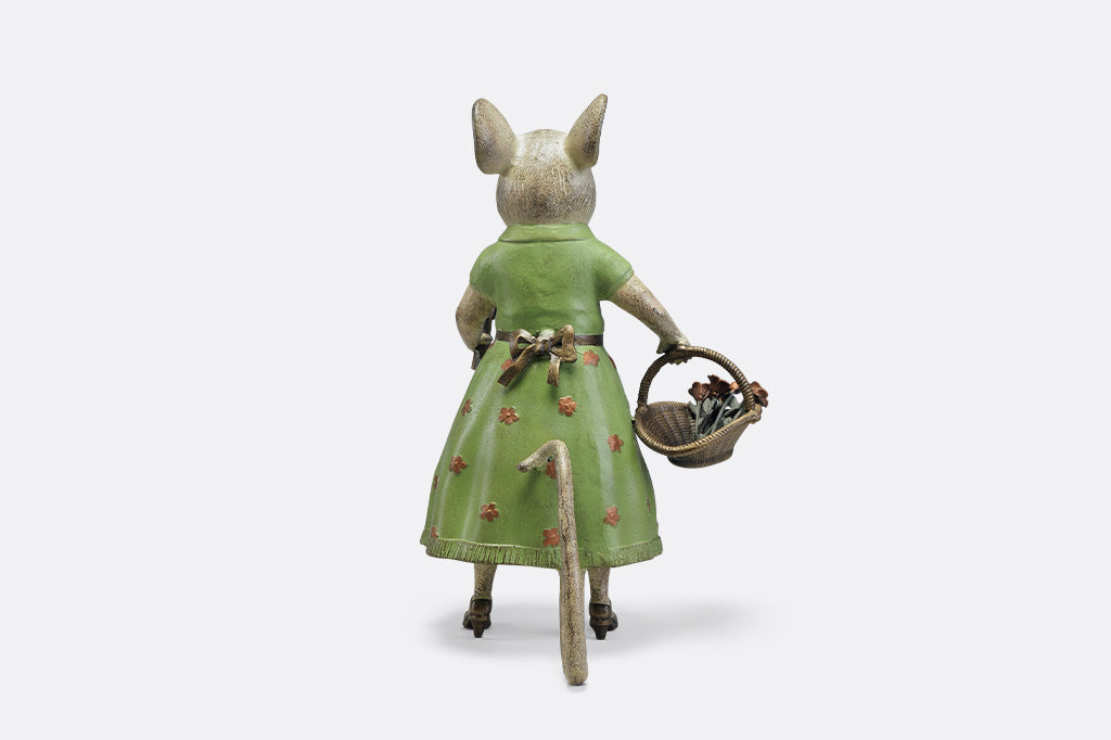A mouse in a green dress holding a shovel and a basket of flowers.
