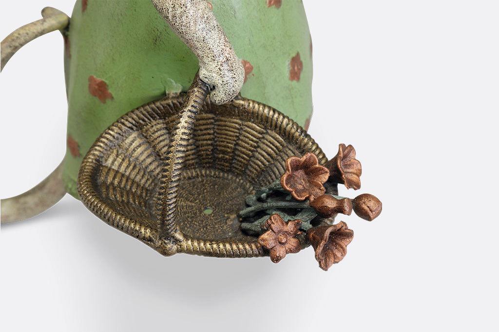 A mouse in a green dress holding a shovel and a basket of flowers.