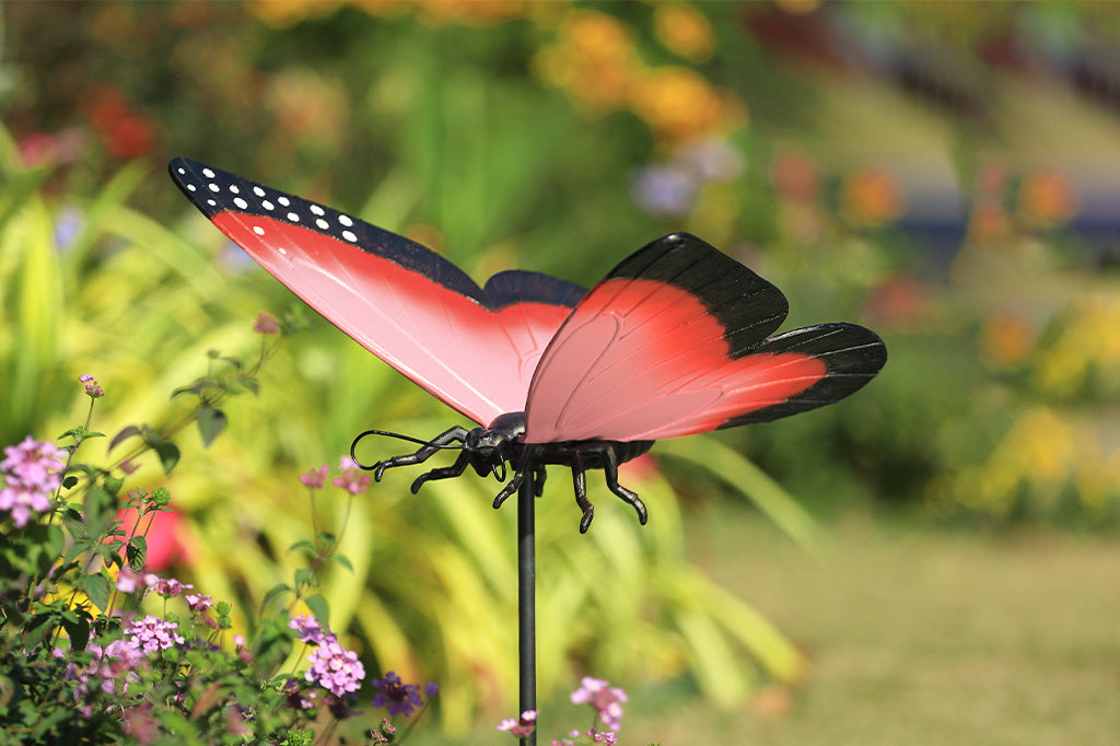 A garden stake sculpture of a pink, red,  and black butterfly.