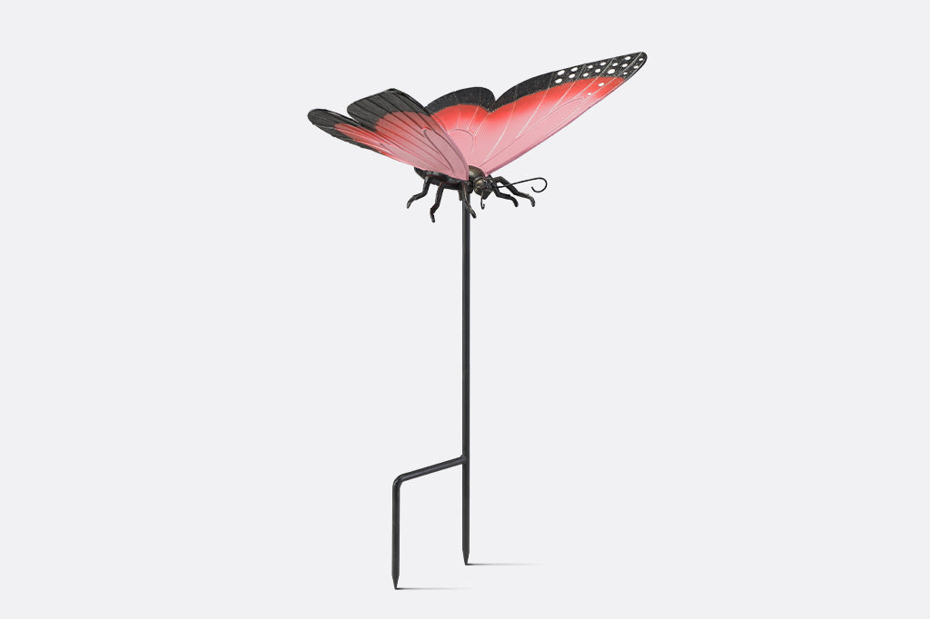 A garden stake sculpture of a pink, red,  and black butterfly.