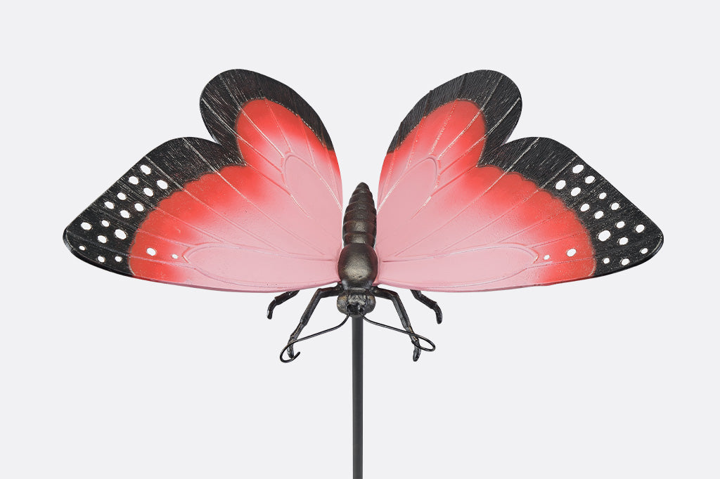 A garden stake sculpture of a pink, red,  and black butterfly.