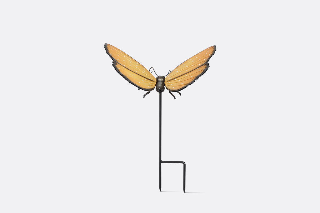 Butterfly-shaped garden stake with orange wings and black body on a white background