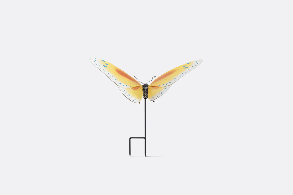 The back view of a Yellow and orange butterfly garden stake with blue dots on white background