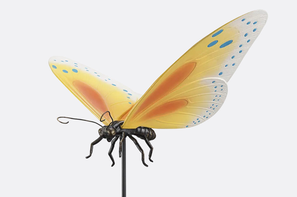 Yellow and orange butterfly garden stake with blue dots on a white background