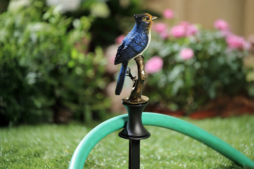 A hose guard sculpture of a Blue Bird sitting upon a twig.