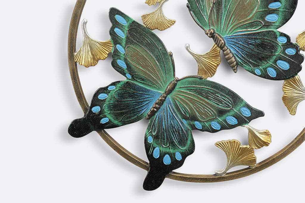 Circular wall art piece with ginkgo flowers and two blue and green butterflies.