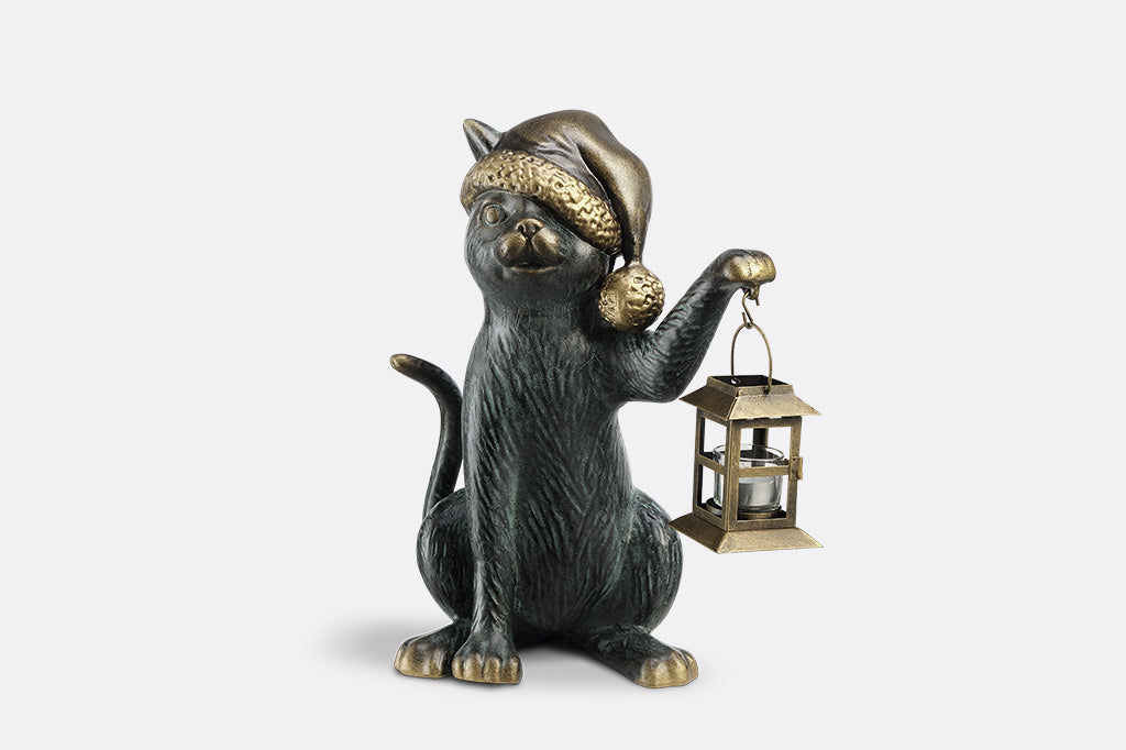 Cat figurine wearing a hat and holding a lantern on a white background