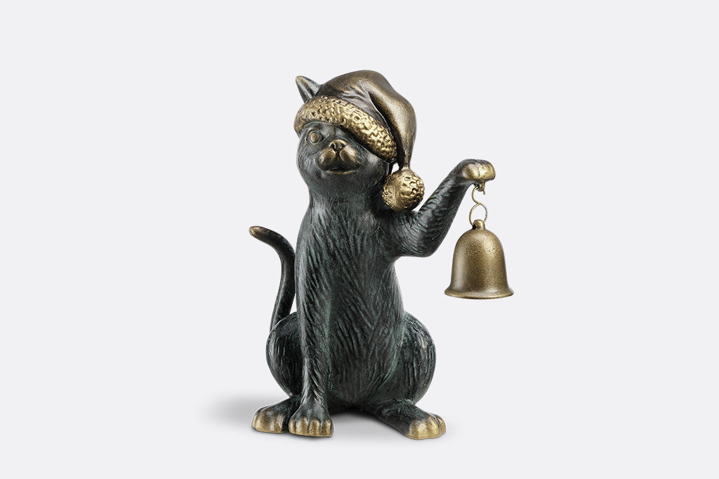 Cat figurine wearing a hat and holding a bell on a white background