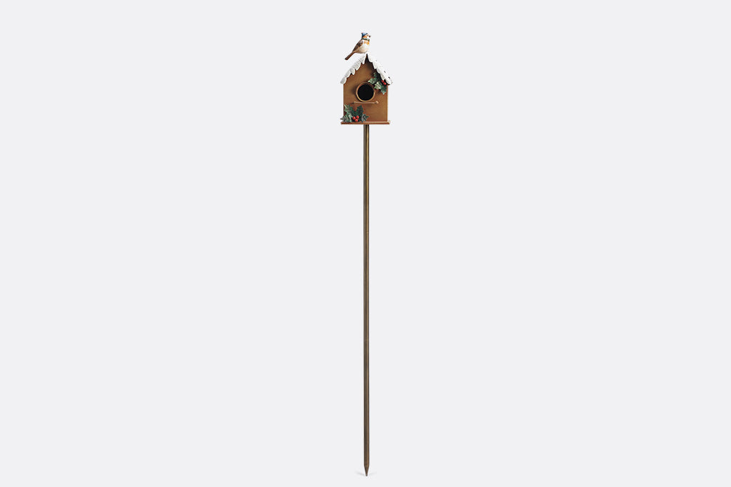 A holiday themed birdhouse with a bird wearing a knitted cap and scarf.